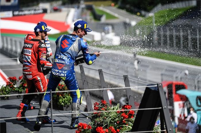 Pembalap Suzuki Ecstar, Joan Mir, merayakan hsail podium MotoGP Austria di Sirkuit Red Bull Ring, Austria, Minggu (16/8/2020). Tampak juga pembalap Ducati, Andrea Dovizioso (merah), yang keluar sebagai pemenang.