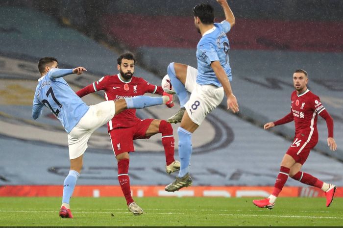 Duel sengit pemian Liverpool, Mohamed Salah dengan dua pemain Manchester City, Joao Cancelo dan Ilkay Guendogan pada laga di Stadion Etihad, Minggu (8/11/2020).