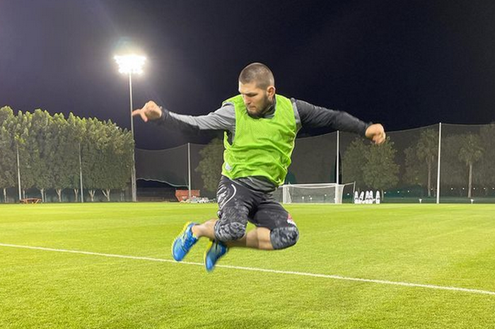 Pensiunan jagoan UFC, Khabib Nurmagomedov berpose di atas rumput lapangan sepak bola.