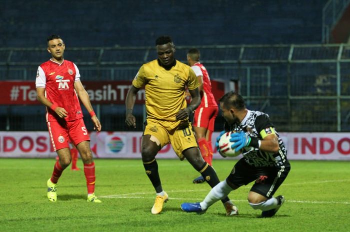 Pemain Bhayangkara Solo FC, Ezechiel N'douassel, berebut bola dengan kiper Persija, Andritany Ardhiyasa dalam laga di Stadion Kanjuruhan, Malang, Rabu (31/3/2021).