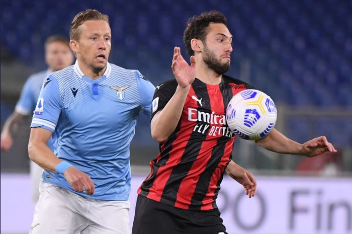 Momen pemain AC Milan, Hakan Calhanoglu berduel dengan gelandang Lazio, Lucas Leiva pada laga yang berlangsung di Stadion Olimpico, Senin (26/4/2021) atau Selasa dini hari WIB.