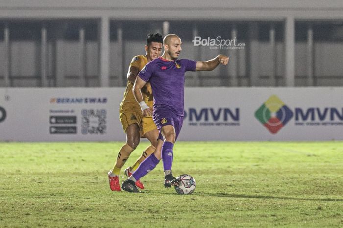 Striker Persik Kediri, Youssef Ezzejjari (kanan), sedang menguasai bola dan dibayangi bek Bhayangkara FC, I Putu Gede Juni Antara (kiri), dalam laga pekan kelima Liga 1 2021 di Stadion Madya, Senayan, Jakarta, 29 September 2021.