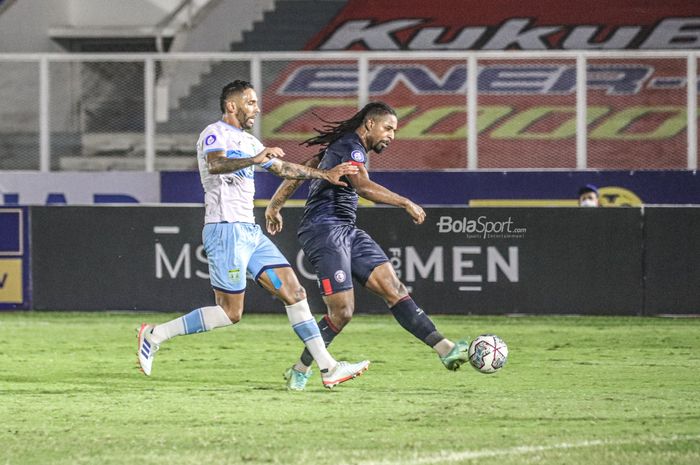 Striker Arema FC, Carlos Fortes (kanan), sedang menendang bola dan dibayangi bek Persela Lamongan, Demerson Bruno Costa (kiri), dalam laga pekan keenam Liga 1 2021 di Stadion Madya, Senayan, Jakarta, 3 Oktober 2021.