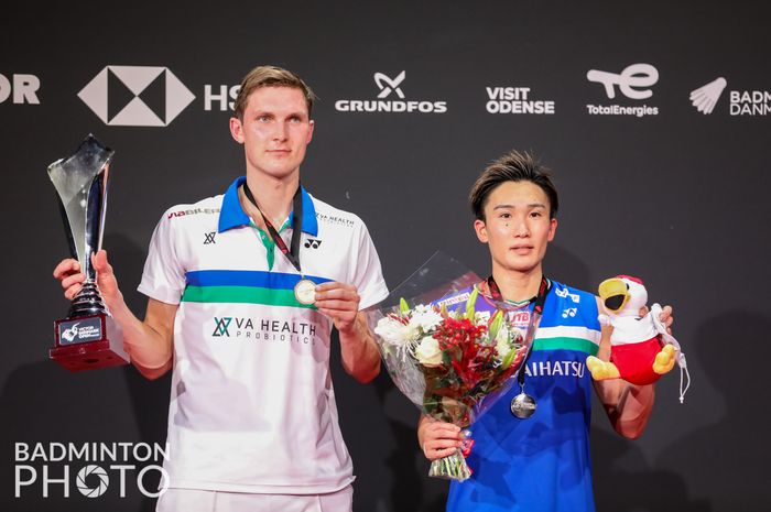 Pebulu tangkis tunggal putra Denmark, Viktor Axelsen (kiri) dan Kento Momota (Jepang) berpose di podium Denmark Open 2021 di Odense Sports Park, Minggu (24/10/2021).