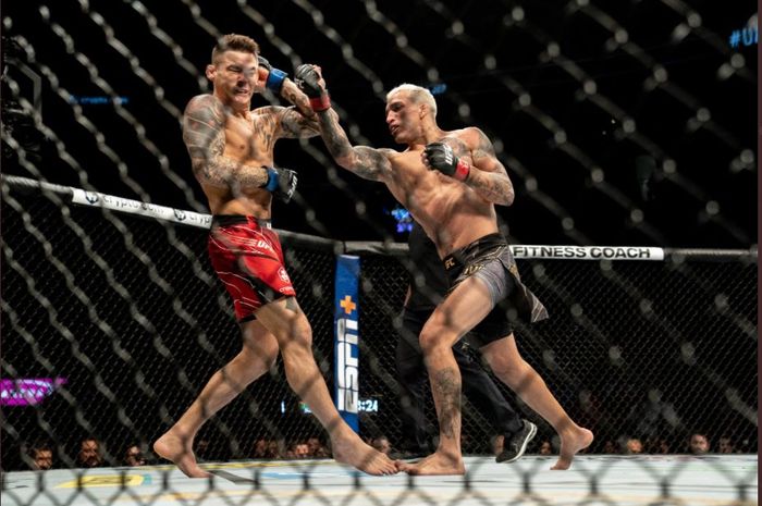 Momen Charles Oliveira (kanan) mengirim pukulan ke Dustin Poirier (kiri) pada laga perebutan gelar juara kelas ringan pda UFC 269 di T-Mobile Arena, Las Vegas, Nevada, Amerika Serikat, Sabtu (11/12/2021).