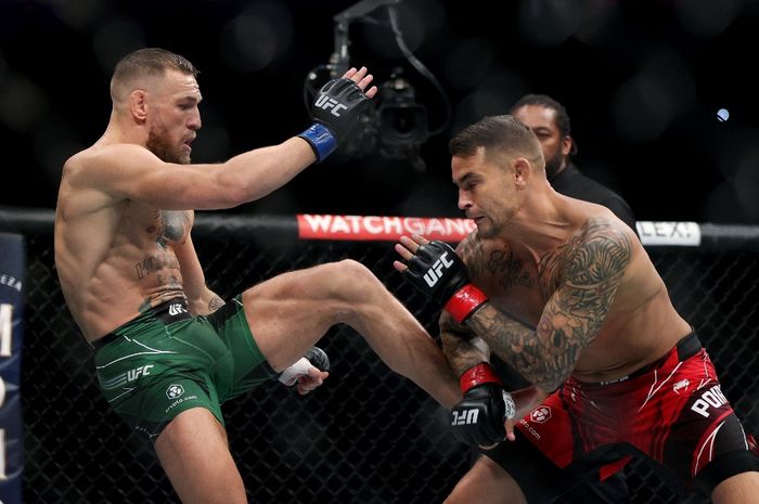 Conor McGregor (kiri) mencoba menendang Dustin Poirier pada pertandingan trilogi mereka di UFC 264 yang digelar di T-Mobile Arena, Nevada, Amerika Serikat, 10 Juli 2022.