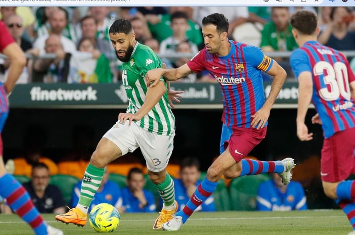 Nabil Fekir (kiri) dan Sergio Busquets (kanan) berebut bola dalam laga antara Real Betis dan Barcelona di Estadio Benito Villamarin pada Sabtu (7/5/2022) waktu setempat.