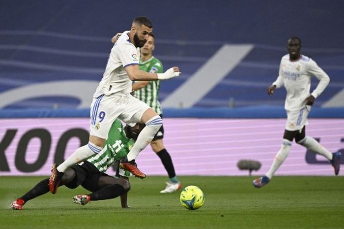 Striker Real Madrid, Karim Benzema, berusaha menghindari tekel dari bek Real Betis, Youssouf Sabaly, dalam laga Liga Spanyol di Stadion Santiago Bernabeu, Jumat (20/5/2022).