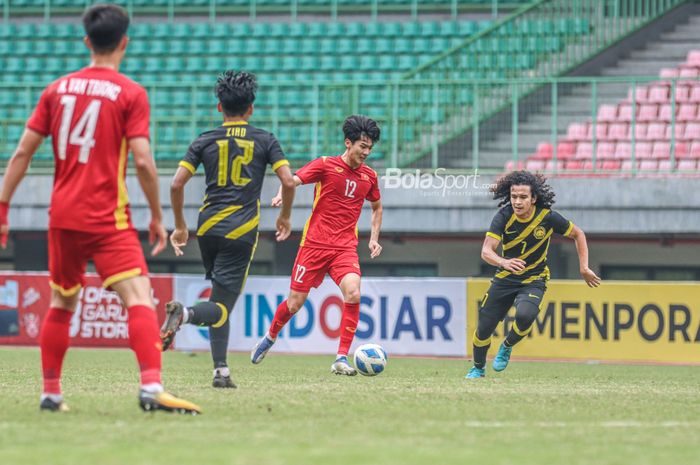 Pemain timnas U-19 Vietnam, Nguyen Bao Long (tengah), sedang menguasai bola dan dibayangi pilar timnas U-19 Malaysia bernama Muhammad Najmudin Akmal Kamal Akmal di Stadion Patriot Candrabhaga, Bekasi, Jawa Barat, 13 Juli 2022.