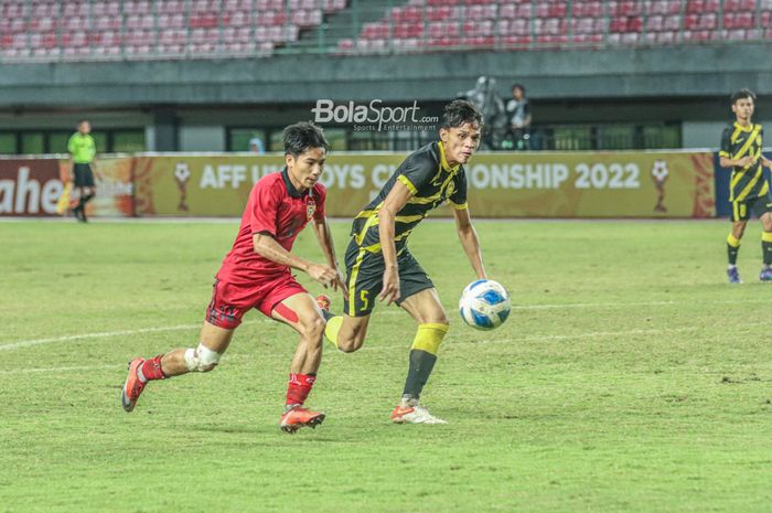 Pemain timnas U-19 Laos, Peeter Phanthavong (kiri), sedang menguasai bola dan dibayangi pilar timnas U-19 Malaysia bernama Muhammad Faiz Amer Runnizar (kanan) saat bertanding di Stadion Patriot Candrabhaga, Bekasi, Jawa Barat, 15 Juli 2022.