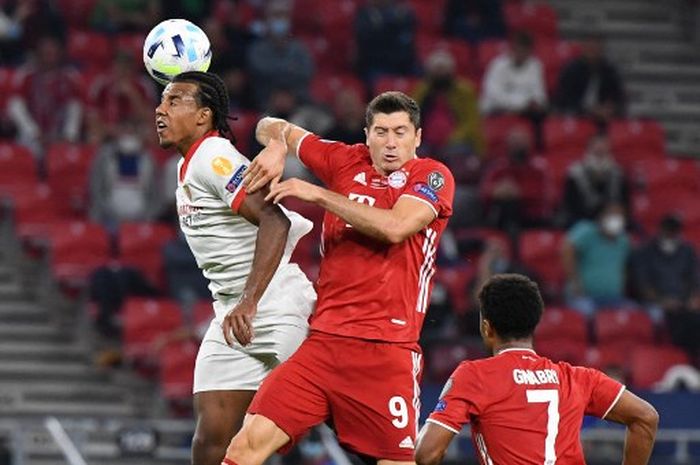 Jules Kounde (kiri) berduel dengan Robert Lewandowski dalam laga Sevilla vs Bayern Muenchen pada Piala Super Eropa di Budapest (24/9/2020).