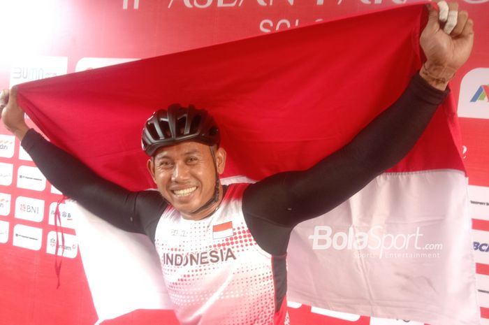 Jaenal Aripin membawa bendera Indonesia untuk merayakan kemenangannya pada lomba lari 200m putra T54 pada ASEAN Para Games 2022 di Stadion Manahan, Solo, Jawa Tengah, 2 Agustus 2022.