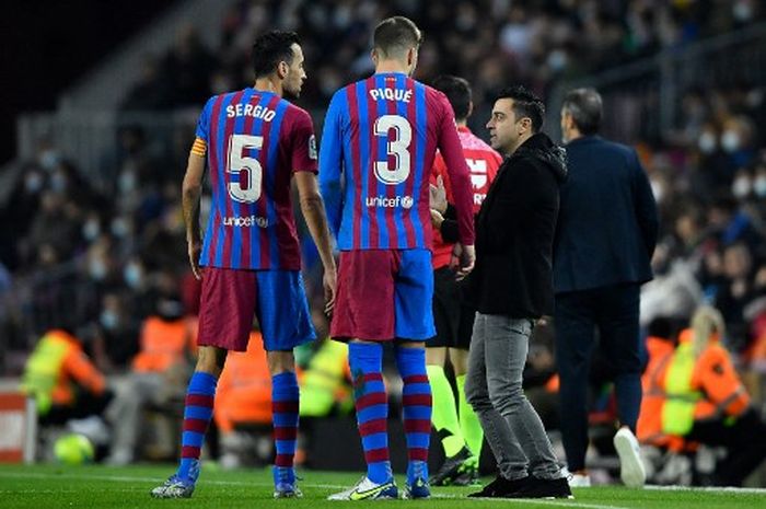 Xavi berbicara dengan Sergio Busquets dan Gerard Pique dalam laga Barcelona vs Espanyol di Camp Nou (20/11/2021).