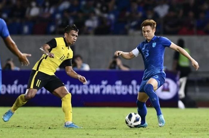 Pemain Timnas Thailand, Theerathon Bunmathan, berduel dengan pemain Timnas Malaysia Safawi Rasid di laga semifinal Piala Raja 2022, Kamis (22/9/2022).