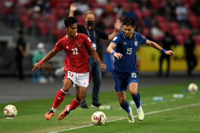 Pilar Timnas Indonesia Pratama Arhan (kiri) berebut bola dengan bek Thailand Narubadin Weerawatnodom dalam final leg kedua Piala AFF 2020 di Stadion Nasional, Singapura, 1 Januari 2022.