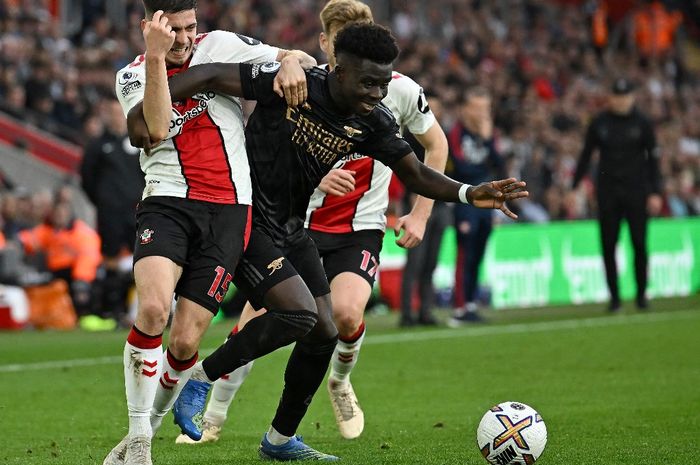 Pemain Arsenal, Bukayo Saka (kanan), berjibaku dengan bek Southampton, Romain Perraud, saat kedua tim bertemu di Stadion St.Mary pada pekan ke-13 Liga Inggris musim 2022-2023, Minggu (23/10/2022)