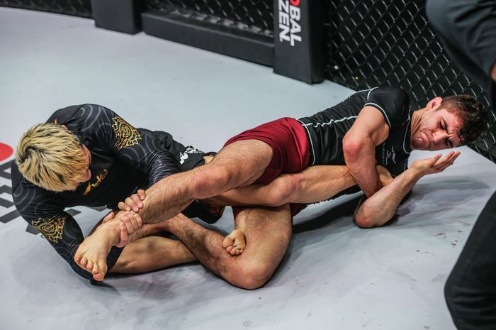 Juara kelas terbang submission grappling ONE Championship, Mikey Musumeci (kanan), tidak percaya Bayanduuren Gantumur tidak menyerah walaupun kakinya sudah terkunci ketat di ONE Fight Night 6, Sabtu (14/1/2023) di Bangkok. 