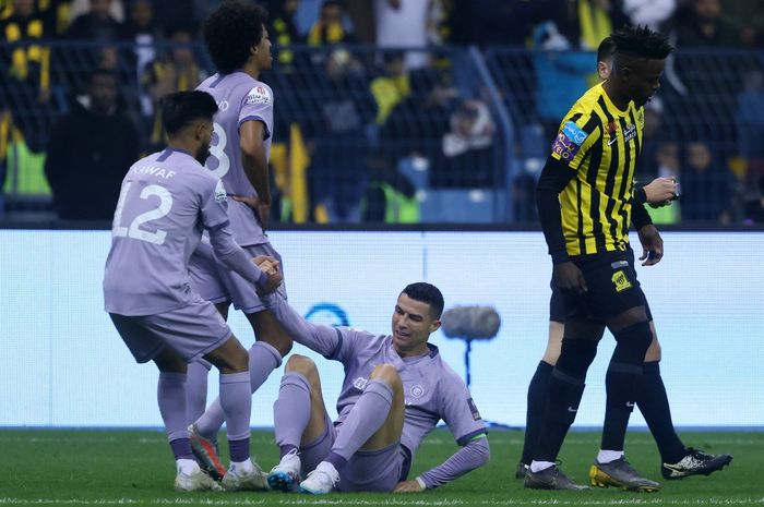 Cristiano Ronaldo harus dibantu rekannya dari Al Nassr usai mendapatkan tekel keras dari pemain Al Ittihad pada laga semifinal Piala Super Saudi, Jumat (27/1/2023) dini hari WIB.