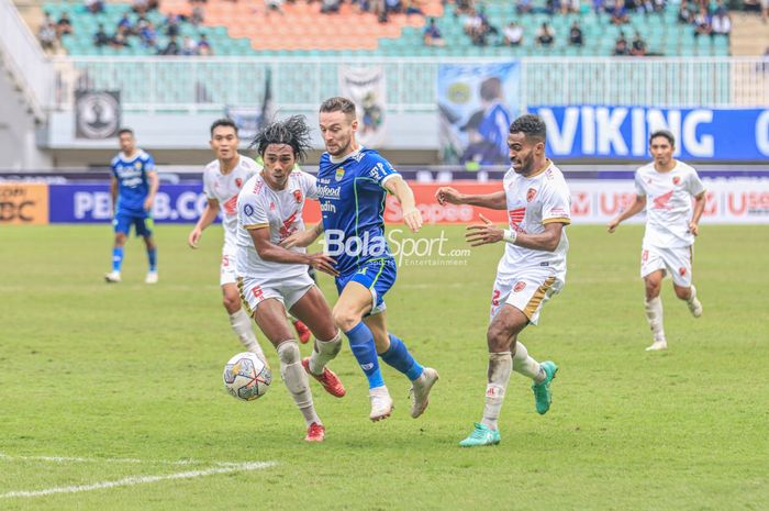 Gelandang Persib Bandung, Marc Klok (tengah), sedang berusaha melewati dua pemain PSM Makassar bernama Erwin Gutawa (kiri) dan Yakob Sayuri (kanan) dalam laga pekan ke-24 Liga 1 2022 di Stadion Pakansari, Bogor, Jawa Barat, Selasa (14/2/2023).