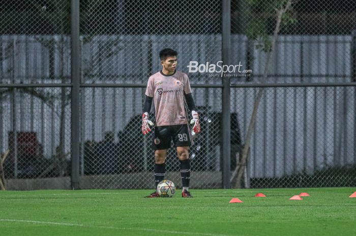 Kiper Persija Jakarta, Cahya Supriadi, sedang menguasai bola dalam sesi latihan di Lapangan Latih JIS (Jakarta International Stadium), Jakarta, Utara, Rabu (12/4/2023) malam.