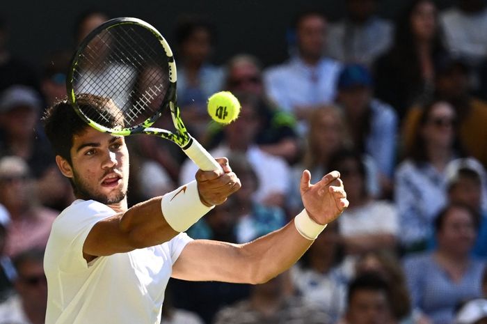 Petenis Spanyol, Carlos Alcaraz, mengembalikan bola ke Holger Rune dari Denmark dalam perempat final tunggal putra Wimbledon 2023 di The All England Lawn Tennis Club in Wimbledon, London, Inggris, 12 Juli 2023.