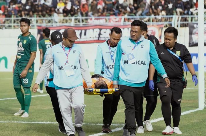 Kiper Persebaya Surabaya, Adhika Ramdhani saat ditandu keluar setelah mengalami benturan dengan pemain Madura United, Minggu (17/9/2023).