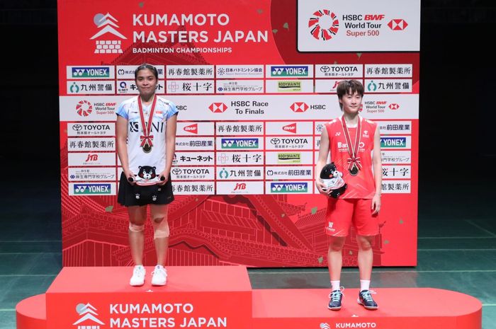 Pebulu tangkis tunggal putri Indonesia, Gregoria Mariska Tunjung, berpose di podium juara usai mengalahkan tunggal putri nomor satu China sekaligus peraih emas Olimpiade Tokyo 2020, Chen Yu Fei (kanan) pada Kumamoto Masters 2023 di Kumamoto Prefectural Gymnasium, Kumamoto, Jepang, Minggu (19/11/2023).