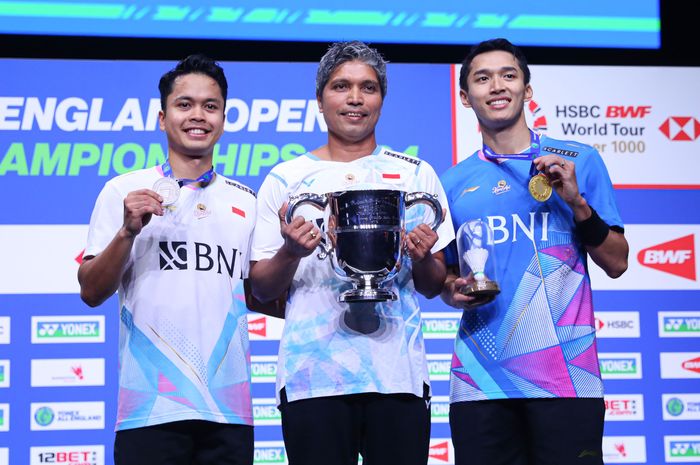 Anthony Sinisuka Ginting, Jonatan Christie, dan pelatih tunggal putra Irwansyah berpose bersama di podium setelah final senegara pada All England Open 2024 di Birmingham, Inggris, 17 Maret 2024. 