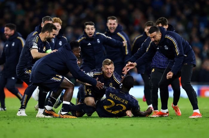 Antonio Ruediger (bawah) diserbu rekan setim usai menentukan kelolosan Real Madrid dalam adu penalti lawan Man City pada perempat final Liga Champions di Etihad Stadium (16/4/2024).