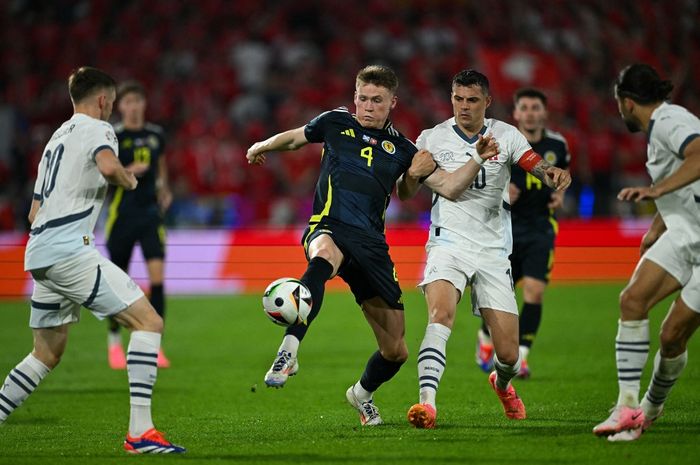 Scott McTominay (4) berduel dengan Granit Xahaka (10) dalam pertandingan antara Skotlandia dan Swiss di Cologne Stadium, Rabu (19/6/2024).