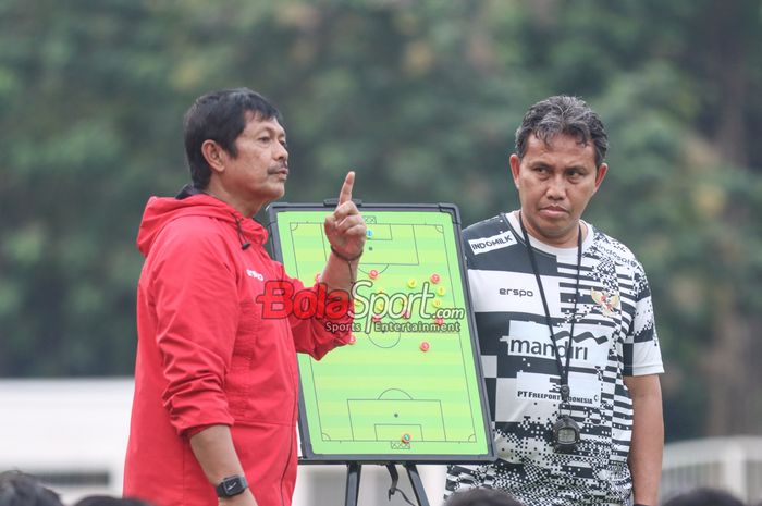 Pelatih timnas U-19 Indonesia, Indra Sjafri (kiri) dan asistennya bernama Bima Sakti (kanan) sedang memantau para pemainnya berlatih di Stadion Madya, Senayan, Jakarta, Senin (1/7/2024).