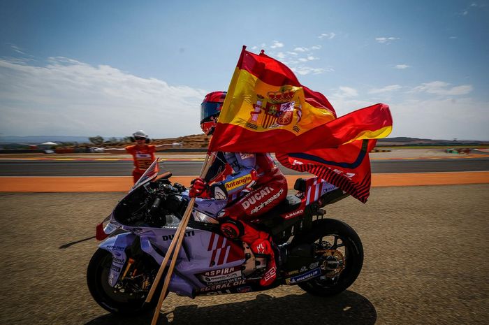 Pembalap Gresini Racing Marc Marquez sedang membawa bendera negaranya Spanyol usai menang pada MotoGP Aragon 2024