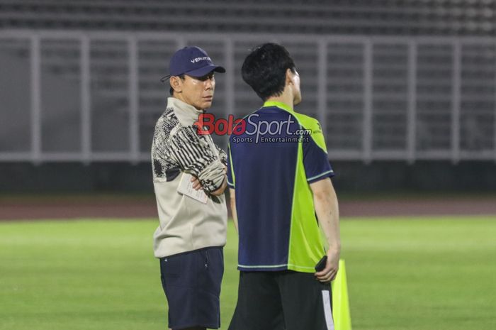 Pelatih timnas Indonesia, Shin Tae-yong (kiri), sedang berkomunikasi dengan salah satu asistennya saat memantau latihan di Stadion Madya, Senayan, Jakarta, Minggu (8/9/2024) malam.