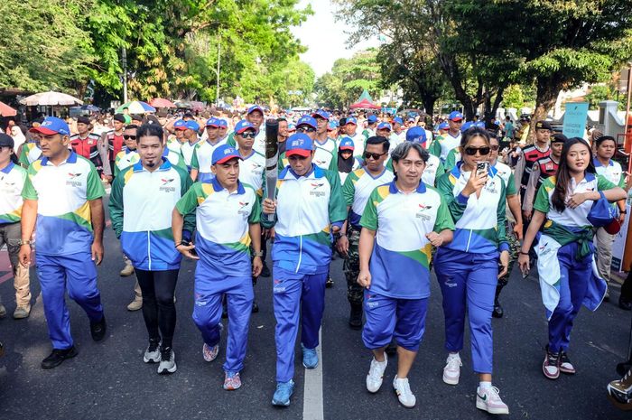 Atlet para bulu tangkis, Suryo Nugroho, membawa obor saat digelar Pawai Obor Pekan Paralimpiade Nasional XVII di area pelaksanaan Solo Car Free Day di jalan Slamet Riyadi, Surakarta, Minggu (29/9/2024).