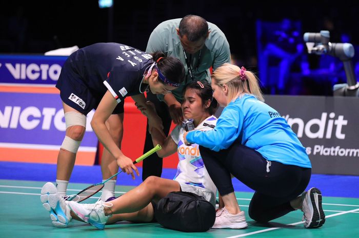 Tunggal putri Indonesia, Gregoria Mariska Tunjung terduduk di tengah lapangan akibat cedera pinggang, dikeliling An Se-young, pelatih Herli Djaenudin dan dokter turnamen pada semifinal Denmark Open 2024, di Jyske Bank Arena, Odense, Denmark, Sabtu (19/10/2024).