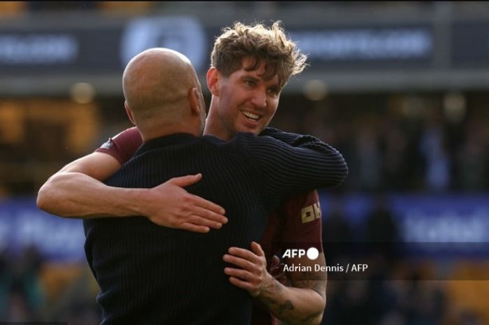 Pep Guardiola memeluk John Stones usai sang bek mencetak gol kemenangan Man City atas Wolverhampton pada duel Liga Inggris di Molineux (20/10/2024).