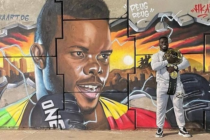 Juara baru kelas berat MMA ONE Championship, Oumar Kane alias Reug Reug, berpose di depan mural dirinya di ibu kota Senegal, Dakar.