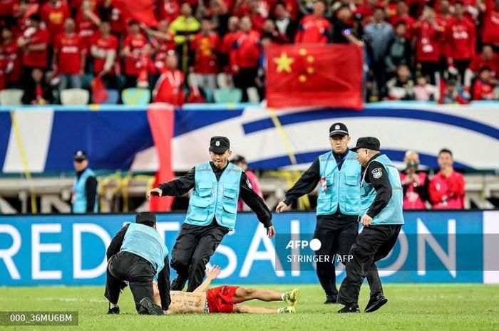 Petugas keamanan mencoba untuk menghentikan aksi suporter Timnas China yang menerobos lapangan saat laga kontra Jepang di Kualifikasi Piala Dunia 2026.