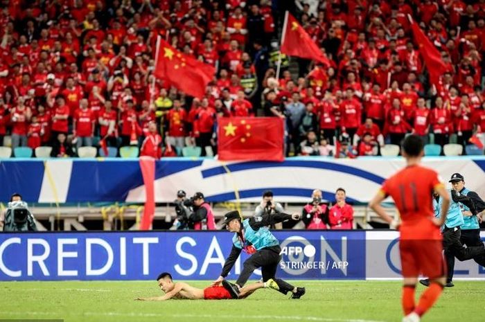 Petugas keamanan menangkap suporter yang menerobos masuk ke lapangan dalam laga Timnas China melawan Jepang di ajang Kualifikasi Piala Dunia 2026.