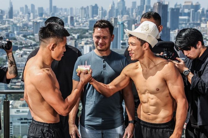 Akbar Abdullaev (kanan) memberikan kue ulang tahun kepada Tang Kai dalam sesi faceoff jelang laga mereka di ONE Fight Night 27 pada Sabtu (11/1/2025) di Bangkok.