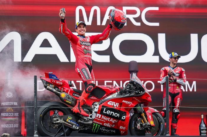 Francesco Bagnaia menyaksikan Marc Marquez berselebrasi atas kemenangan pada balapan MotoGP Belanda 2025.