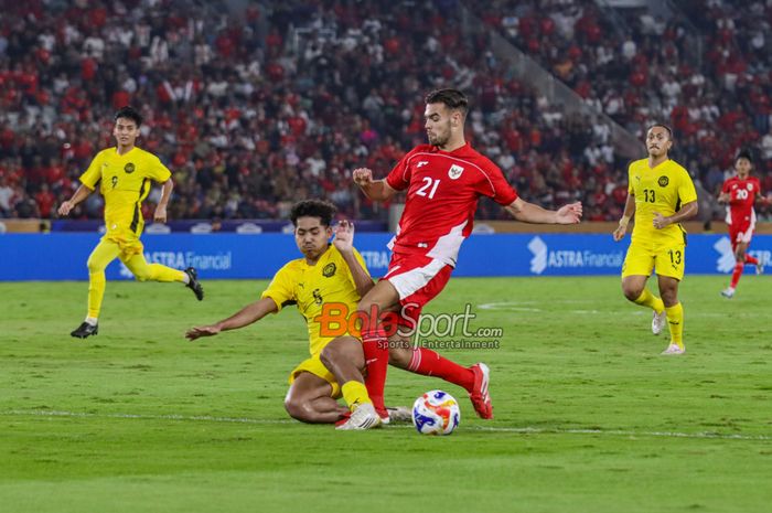 Muhammad Shafizan Bin Mohamad Arshad (kiri) sedang menekel bola yang dikuasai Jens Raven (kanan) dalam laga babak penyisihan Grup A Piala AFF U-23 2025 antara Timnas U-23 Indonesia versus Timnas U-23 Malaysia di Stadion Utama Gelora Bung Karno, Senayan, Jakarta, Senin (21/7/2025).