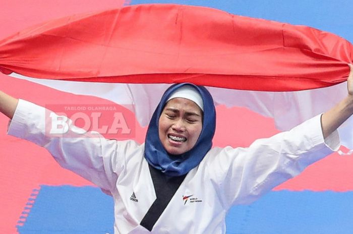  Atlet taekwondo, Defia Rosmaniar, merayakan keberhasilan meraih medali emas pada nomor poomsae individu putri di Plenary Hall JCC, Jakarta, Minggu (19/8/2018). 