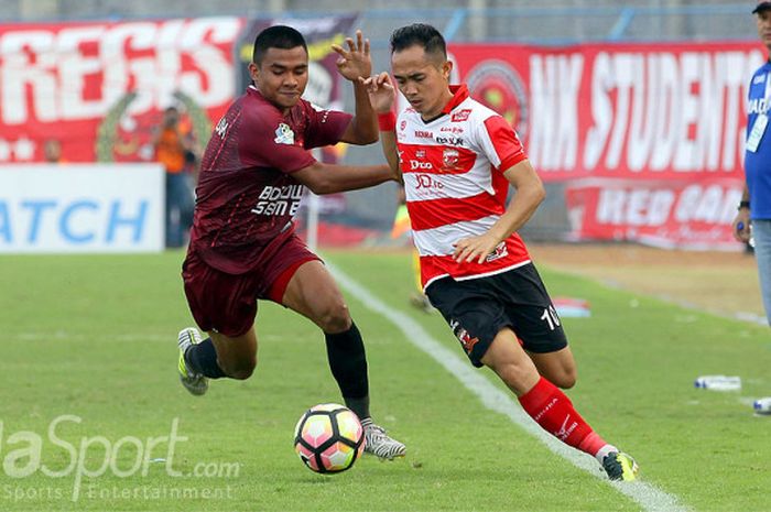 Gelandang Madura United, Slamet Nurcahyo (kanan), berebut bola dengan gelandang PSM Makassar, Asnawi Mangkualam Bahar, dalam laga pekan ke-17 Liga 1 Stadion Gelora Bangkalan, Jawa Timur, Sabtu (29/07/2017) sore.