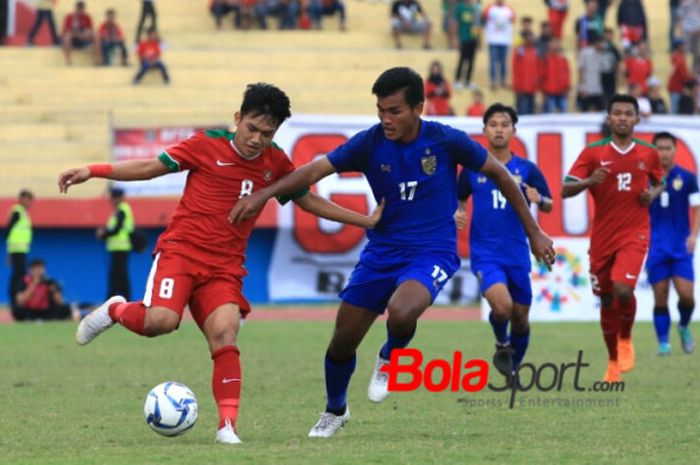 Penyerang timnas U-19 Indonesia, Witan Sulaeman (kiri) mencoba menjauhkan bola dari pemain timnas U-19 Thailand, Kritsana Daokrajai pada laga perebutan peringkat tiga Piala AFF U-19 2018 di Stadion Gelora Delta, Sidoarjo, 14 Juli 2018.  