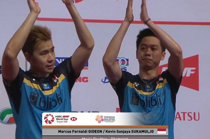 Marcus Fernaldi Gideon (kiri) dan Kevin Sanjaya Sukamuljo (kanan) saat berdiri di podium juara Malaysia Masters 2019 usai memenangkan duel final yang digelar pada Minggu (20/1/2019).