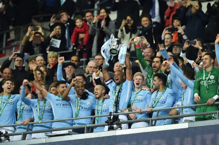 Kapten Manchester City, Vincent Kompany, mengangkat trofi Piala Liga Inggris seusai mengalahkan Arsenal dalam laga final di Stadion Wembley, London, pada 25 Februari 2018.