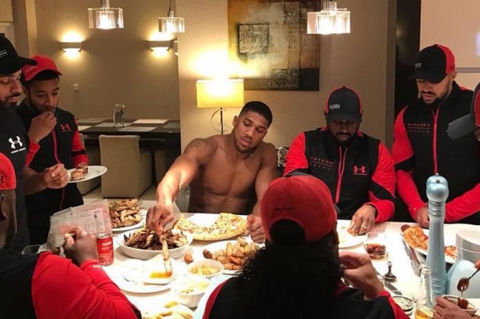 Anthony Joshua (telanjang dada) saat menikmati makan malam bersama timnya.