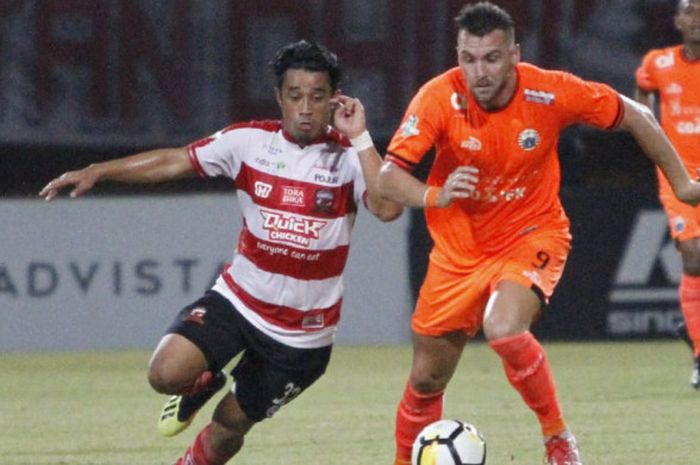 Bek sayap Madura United, Beny Wahyudi mengawal pergerakan penyerang Persija Jakarta, Marko Simic pada laga di Stadion Gelora Ratu Pamelingan, Pamekasan, Madura, Minggu (14/10/2018).