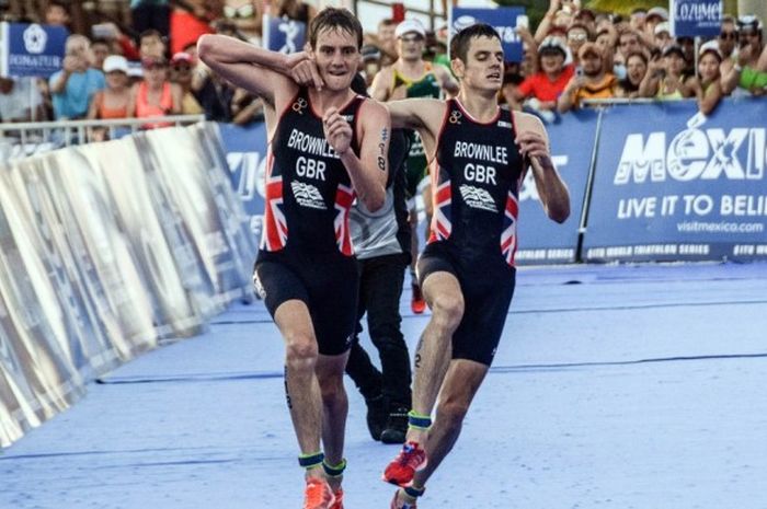 Atlet triatlon Inggris Raya, Alistair Brownlee (kiri), membantu sang adik, Jonathan Brownlee, untuk melintasi garis finis ITU World Triathlon Series 2016 in Cozumel, Mexico, Minggu (18/9/2016). Alistair finis ketiga, sedangkan Jonathan finis kedua.